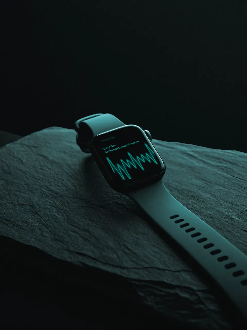 Fitness-Smartwatch mit glühender Teal-Pulslinie auf dunklem Schiefer